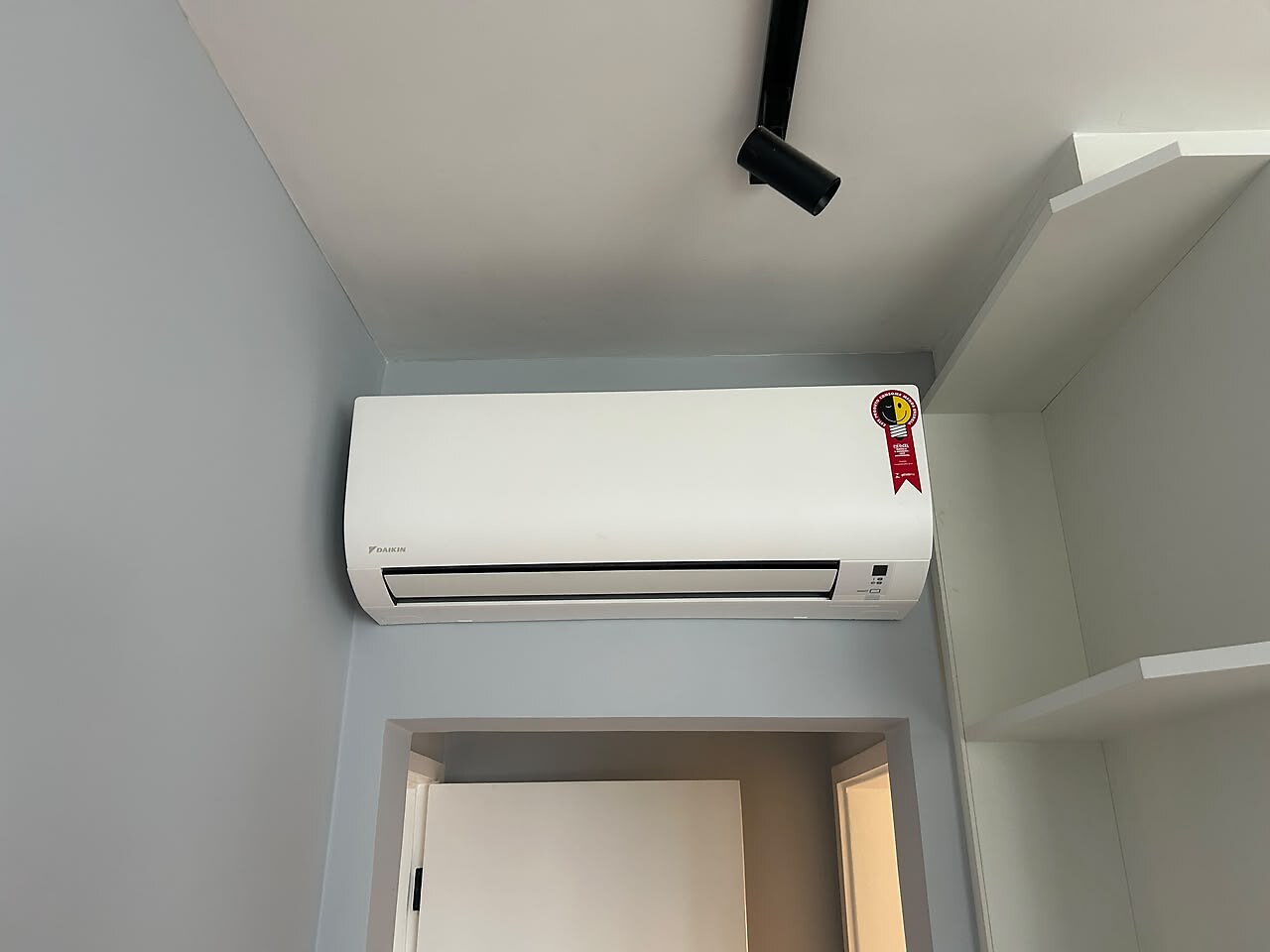 Evaporadora de ar-condicionado instalada na parede acima do vão de uma porta, distribuindo o ar para outro ambiente