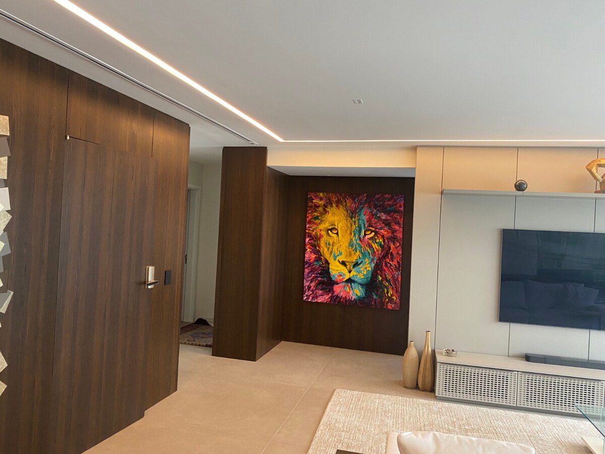 Difusor linear de ar-condicionado embutido no forro de gesso junto a um painel de madeira, em ambiente integrado