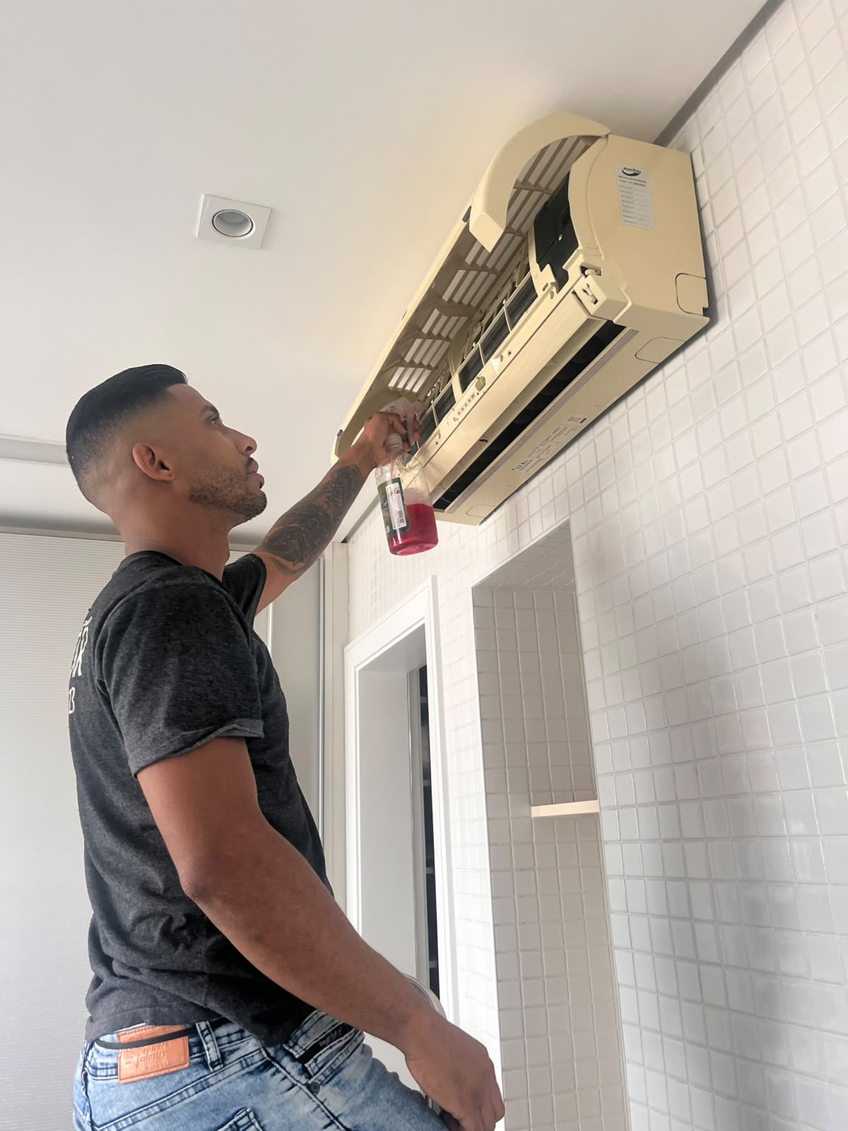 Técnico aplicando produto de limpeza no interior de uma evaporadora hi-wall com a frente aberta