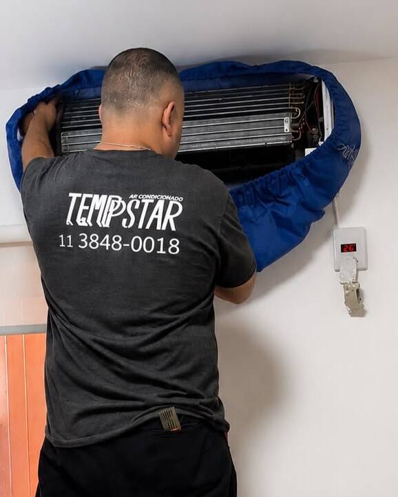 Técnico posicionando a bolsa coletora na serpentina de um ar-condicionado hi-wall